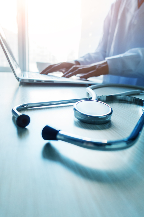 Doctor typing information on the computer in office